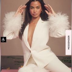 a woman sitting on top of a pink floor wearing a white suit and feather boa