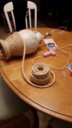 a wooden table topped with two white chairs and a rope wrapped around the top of it