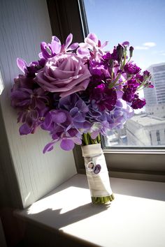 a bouquet of purple flowers sitting on top of a window sill next to a window