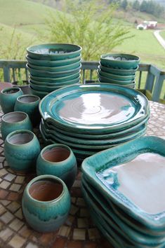 a table topped with lots of green plates and bowls on top of a wooden table