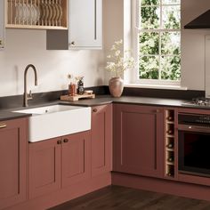 a kitchen with pink cabinets and an oven in the corner, next to a window