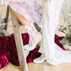 a woman in white boots is sitting on a chair with her dress draped over her