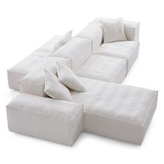 a large white couch with pillows on it's back and side ends, facing away from the camera