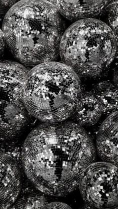 black and white photograph of disco balls with silver sequins on them, all stacked together