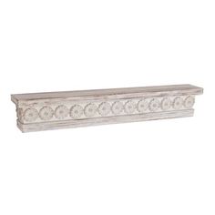 a white wooden shelf with decorative designs on the top and bottom, against a white background