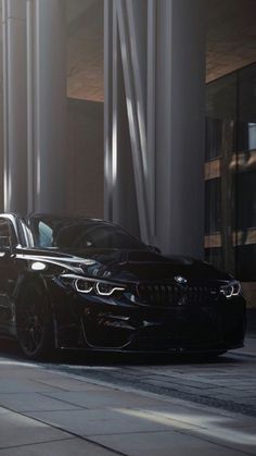 a black car parked on the side of a street next to tall buildings and columns