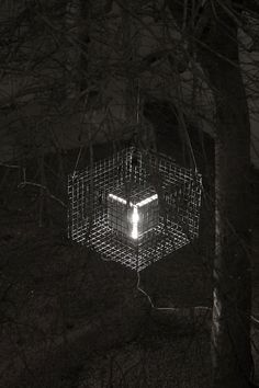 a cage is lit up in the dark with light coming from it's top