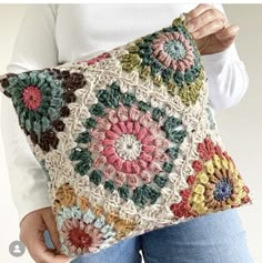 a woman is holding a crocheted pillow with flowers on the front and sides