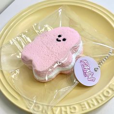 there is a pink cookie shaped like a dog on a plate with a name tag