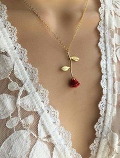 a close up of a woman wearing a necklace with a rose on it's side