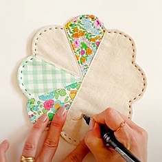 a woman is working on a piece of fabric with a pen in her left hand