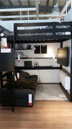 a loft bed with desk underneath it in a living room next to a tv on a stand