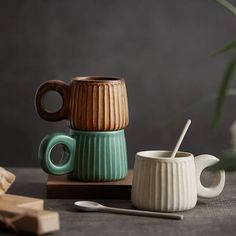 two mugs sitting next to each other on top of a wooden tray with spoons