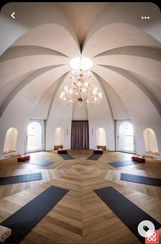 an empty room with several yoga mats on the floor and chandelier hanging from the ceiling