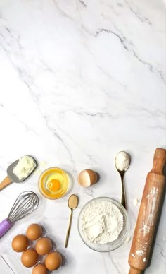 an assortment of ingredients on a marble countertop with rolling pins, eggs and flour