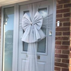 a white bow on the front door of a house that has been decorated with tulle