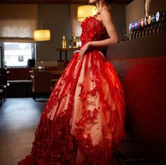 a woman in a red dress standing next to a bar