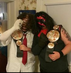 two men with their faces painted like wrestling masks, one wearing a red tie and the other in black