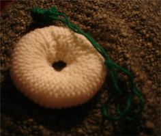 a white crocheted donut sitting on top of a brown carpet next to a green string