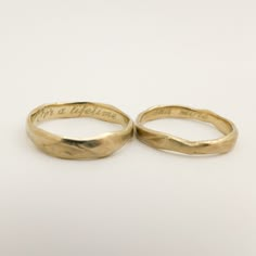 two gold wedding rings with words engraved on them