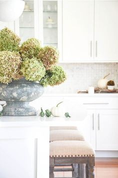 a vase filled with flowers sitting on top of a counter next to two stools