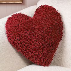 a red heart shaped pillow sitting on top of a white couch