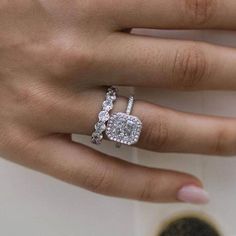 a woman's hand with a diamond ring on top of her finger and an engagement band