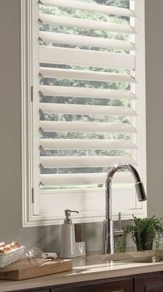 a kitchen window with white blinds in it