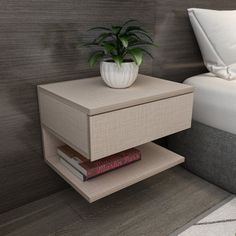 a nightstand with a plant on it next to a bed