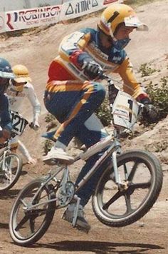 three men riding bikes down a dirt road