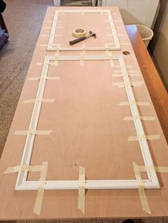 a wooden table with tape taped around the edges and tools on it, in front of a kitchen counter