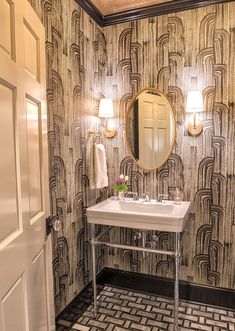 a bathroom with a sink and mirror next to a door that has a pattern on it