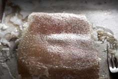 a piece of cake with powdered sugar on top and a fork next to it