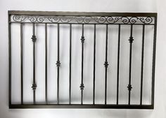 an iron fence with decorative designs on it against a white wall in the corner of a room