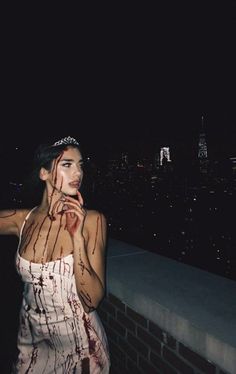 a woman with blood all over her body standing on top of a building at night