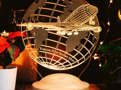 an illuminated globe sits next to a potted plant