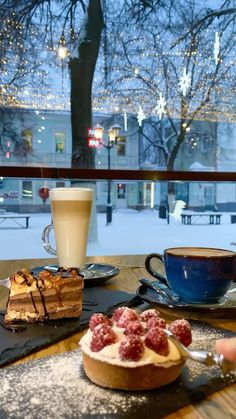 a table topped with desserts next to a cup of coffee on top of a wooden table