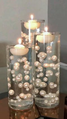 two glass vases filled with pearls and lit candles