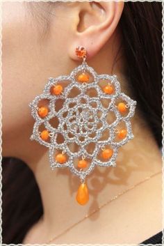 a close up of a person wearing some kind of earring with orange beads on it