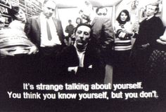 a group of people standing around each other in front of a sign that says it's strange talking about yourself