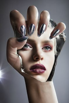 a woman holding her hand up to her face with nail polish on it's nails