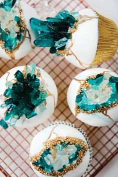 some white eggs with green and gold decorations on top of each one, sitting on a wire rack