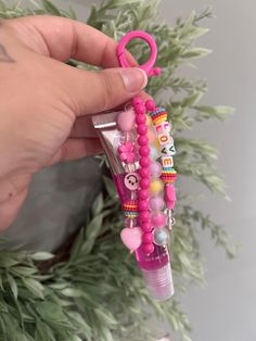 a hand holding a pink beaded keychain with charms and beads on it