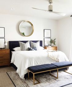 a bed room with a neatly made bed and a large mirror on the wall above it