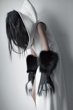 a woman with long black hair wearing a white dress and fur stole around her neck