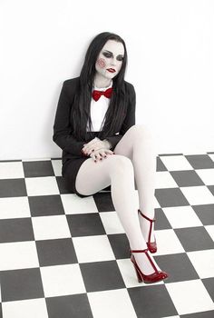 a woman dressed in black and white sitting on a checkered floor