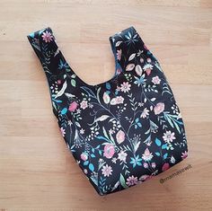 a black floral bag sitting on top of a wooden floor