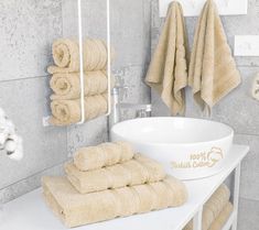 towels are lined up on a white counter in a bathroom with a sink and towel rack