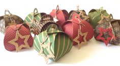 six ornament shaped boxes with bows and stars hanging from the top, on a white surface