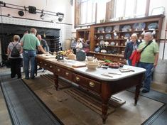 people are standing around a table in a room with many dishes and bowls on it